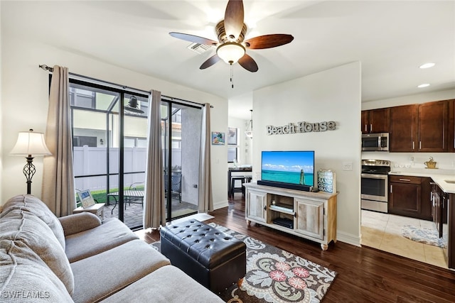 living room featuring a wealth of natural light, ceiling fan, and dark wood-type flooring