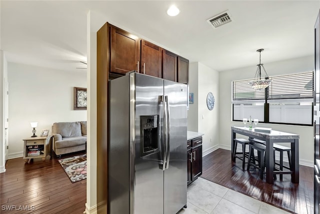 kitchen with dark brown cabinetry, a notable chandelier, stainless steel fridge, pendant lighting, and light wood-type flooring