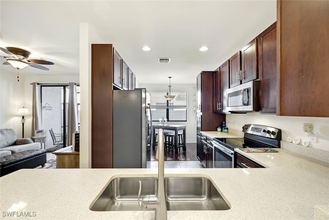 kitchen featuring stainless steel appliances, ceiling fan, sink, decorative light fixtures, and dark hardwood / wood-style floors