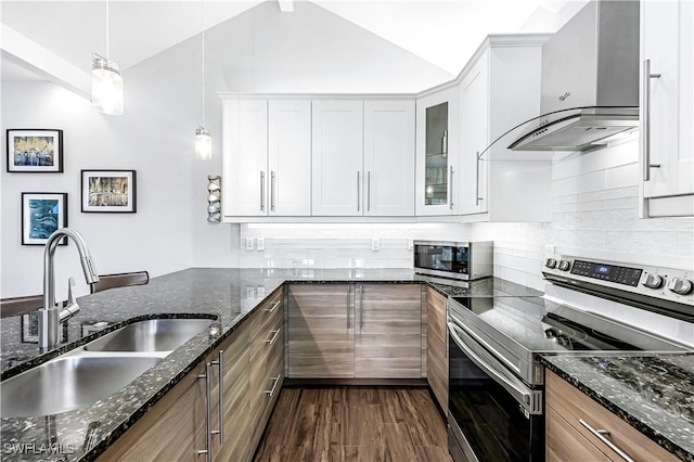 kitchen featuring white cabinets, dark stone countertops, wall chimney range hood, and stainless steel appliances