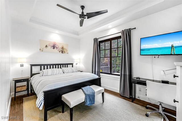 bedroom with a tray ceiling, ceiling fan, and dark wood-type flooring