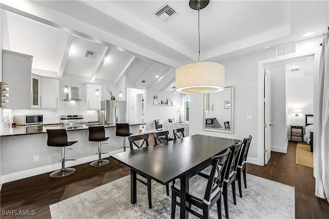 dining area featuring dark hardwood / wood-style flooring and lofted ceiling with beams