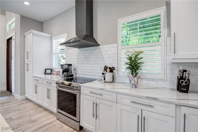 kitchen with plenty of natural light, wall chimney exhaust hood, and stainless steel electric range