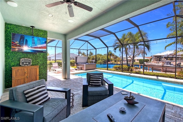 view of swimming pool featuring an outdoor living space, glass enclosure, ceiling fan, a patio, and a hot tub