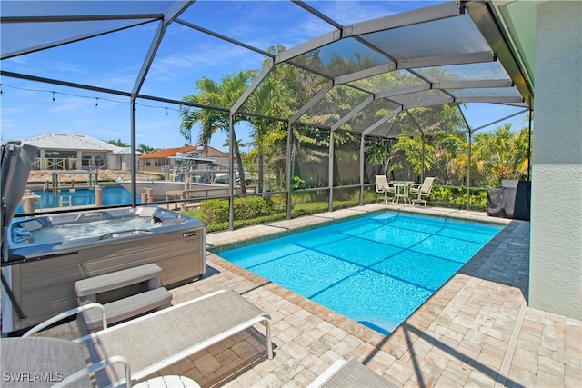 view of pool with a water view, a hot tub, a lanai, and a patio area