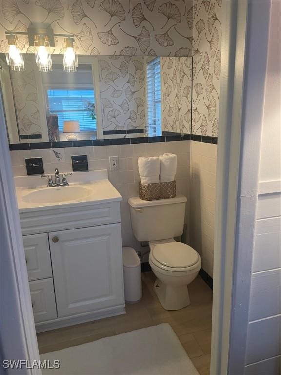 bathroom featuring vanity, tile walls, and toilet