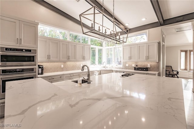 kitchen with sink, pendant lighting, and light stone counters