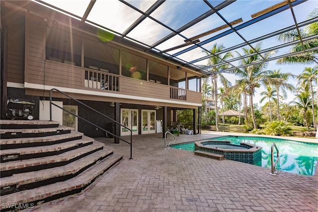 view of pool with a patio, glass enclosure, and an in ground hot tub