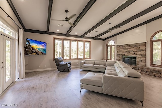 living room with french doors, ceiling fan, a stone fireplace, and lofted ceiling with beams