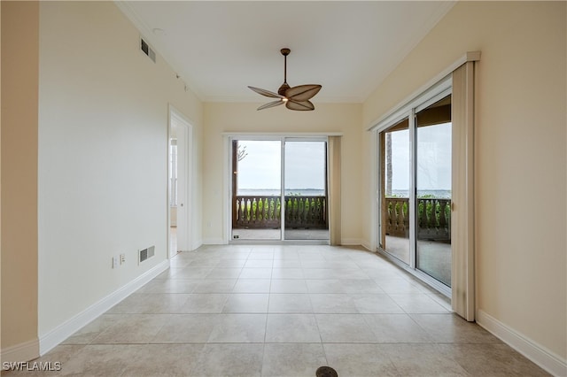 tiled empty room with ceiling fan and crown molding