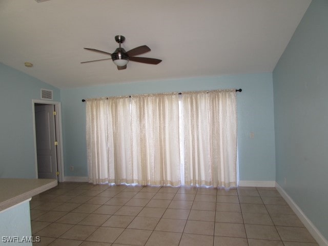 tiled spare room with ceiling fan, plenty of natural light, and lofted ceiling