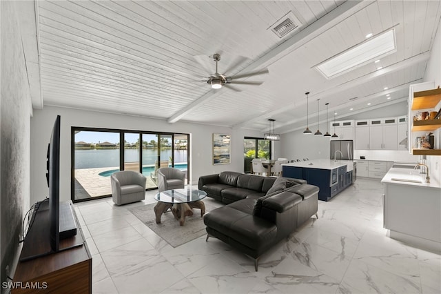 living room with vaulted ceiling with skylight, ceiling fan, a healthy amount of sunlight, and wooden ceiling