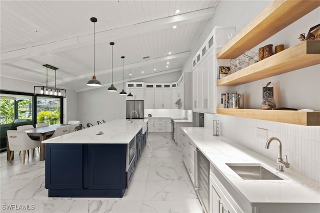 kitchen with sink, lofted ceiling with beams, decorative light fixtures, white cabinets, and a large island