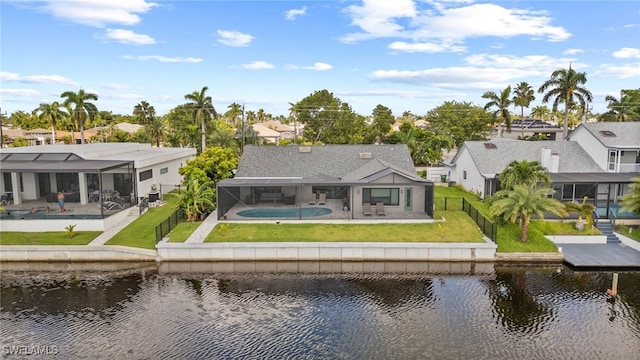 back of house featuring a yard, a water view, a patio, and a pool with hot tub