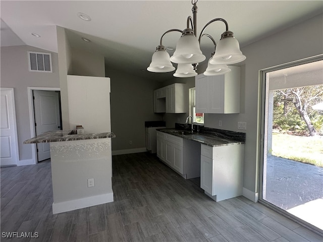 kitchen with a chandelier, dark hardwood / wood-style floors, hanging light fixtures, and lofted ceiling