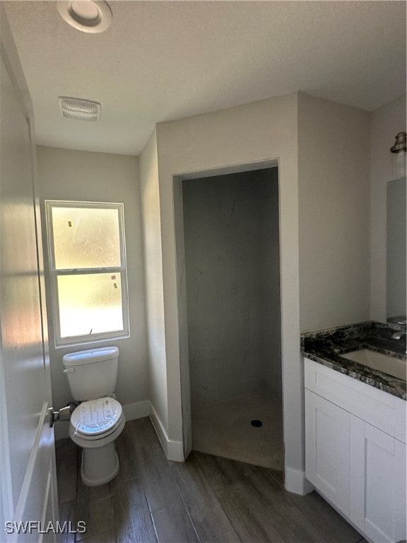 bathroom featuring a shower, wood-type flooring, vanity, and toilet