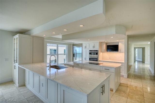 kitchen with white cabinets, stainless steel appliances, light stone countertops, and a large island