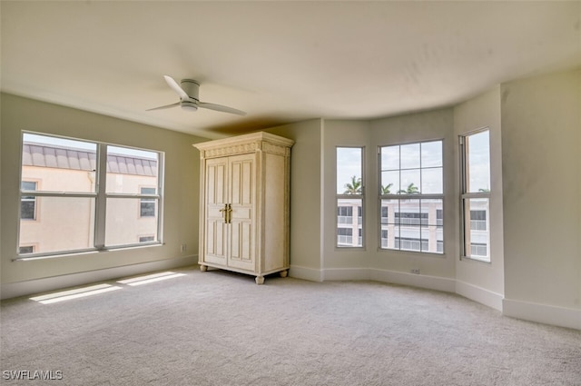 unfurnished bedroom featuring multiple windows, light carpet, and ceiling fan