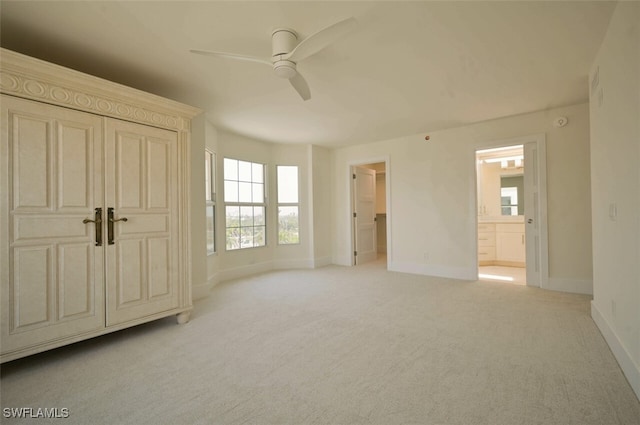 unfurnished bedroom with ensuite bath, light colored carpet, ceiling fan, a spacious closet, and a closet