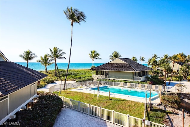 view of pool with a water view and a yard