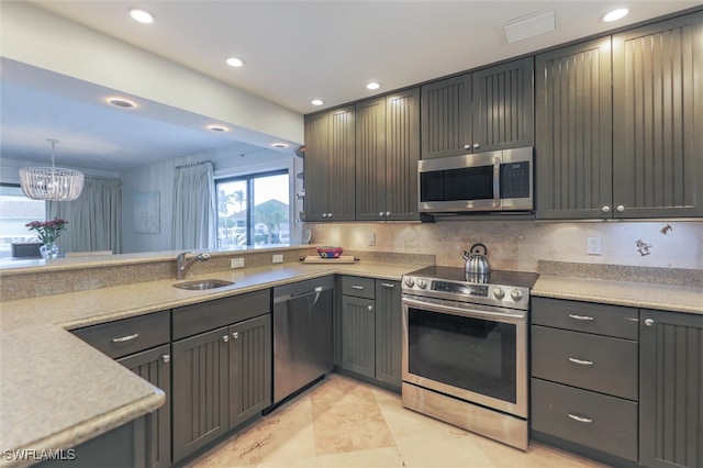 kitchen with tasteful backsplash, stainless steel appliances, sink, pendant lighting, and a notable chandelier