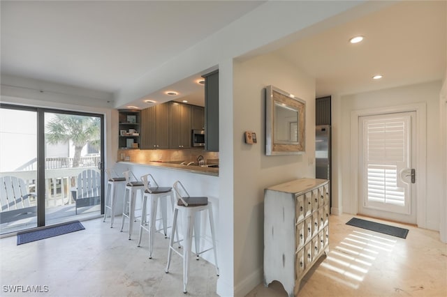 kitchen featuring kitchen peninsula, decorative backsplash, stainless steel appliances, and a breakfast bar area