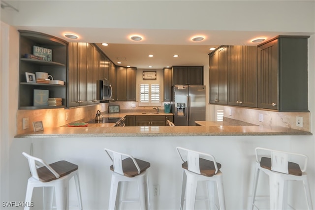 kitchen featuring light stone countertops, a kitchen bar, kitchen peninsula, and stainless steel appliances