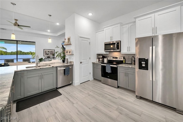 kitchen with appliances with stainless steel finishes, gray cabinetry, ceiling fan, sink, and light hardwood / wood-style flooring