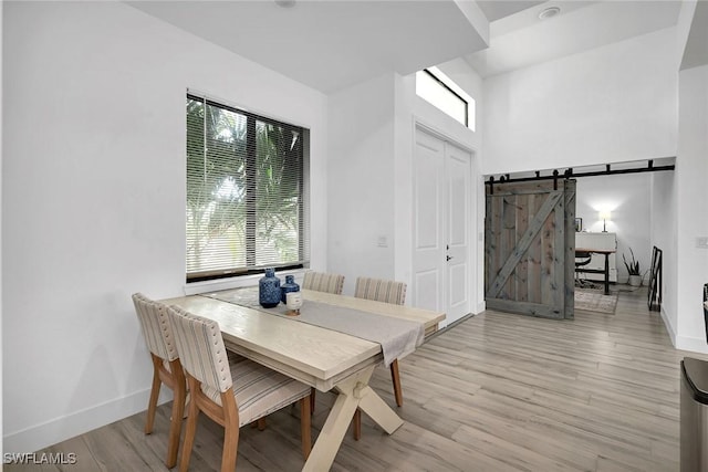 dining space with a barn door and light hardwood / wood-style flooring