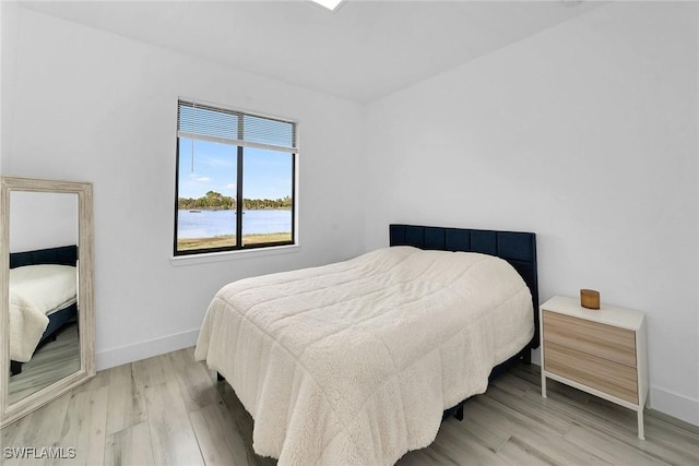 bedroom featuring a water view and wood-type flooring