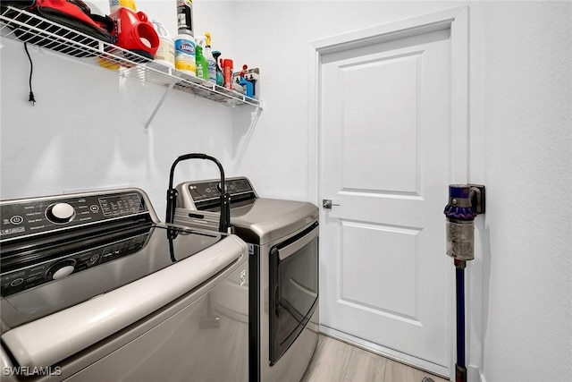 laundry area with washer and clothes dryer and light hardwood / wood-style flooring