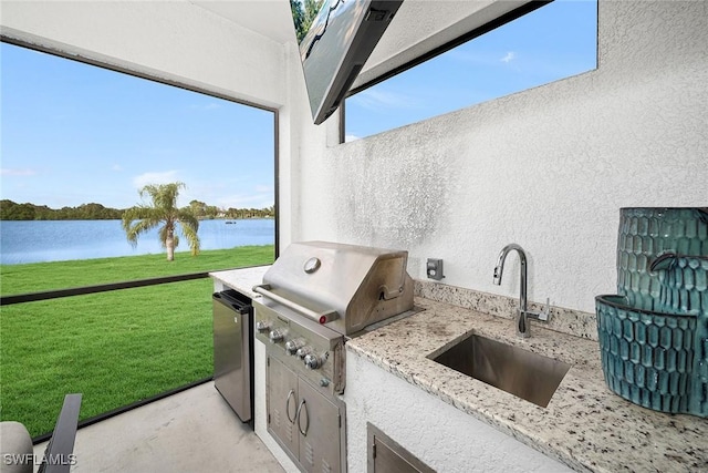 view of patio / terrace with area for grilling, sink, a water view, and exterior kitchen