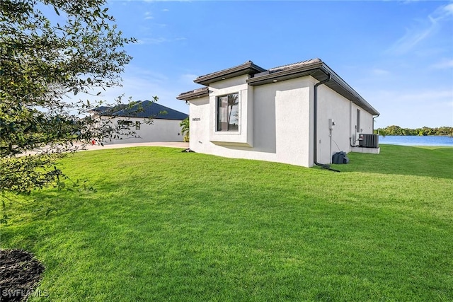 rear view of house featuring central AC, a yard, and a water view