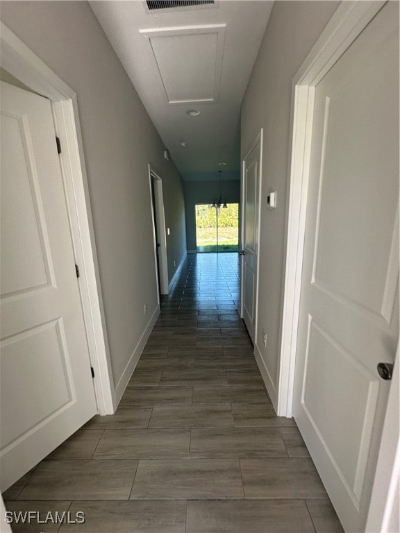 corridor featuring a chandelier and dark wood-type flooring