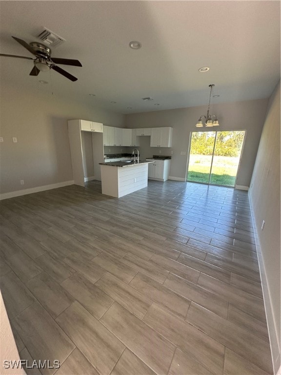 unfurnished living room with light hardwood / wood-style flooring, ceiling fan with notable chandelier, and sink