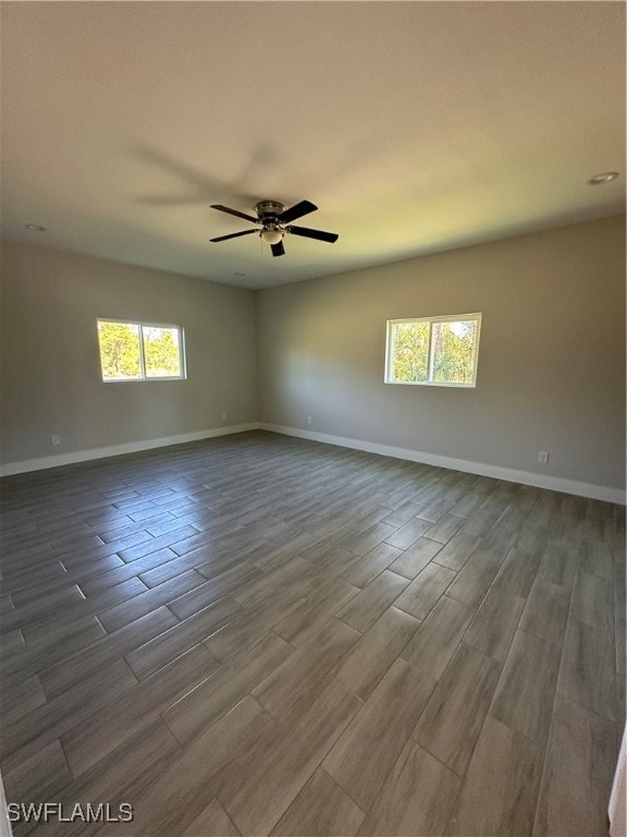 spare room featuring ceiling fan, wood-type flooring, and a wealth of natural light