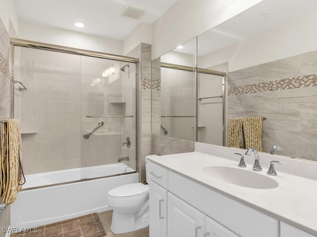 full bathroom with tile patterned floors, vanity, bath / shower combo with glass door, and toilet