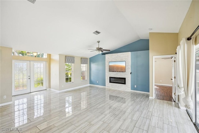 unfurnished living room with plenty of natural light, lofted ceiling, a fireplace, and french doors