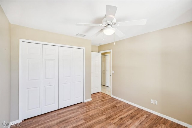 unfurnished bedroom with ceiling fan, a closet, and light wood-type flooring