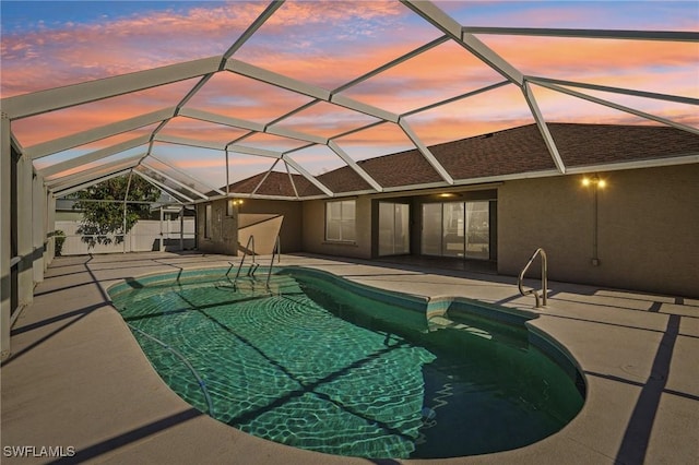 pool at dusk with a lanai and a patio area