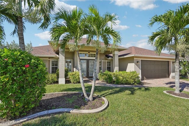 view of front of home with a garage, driveway, french doors, a front lawn, and stucco siding