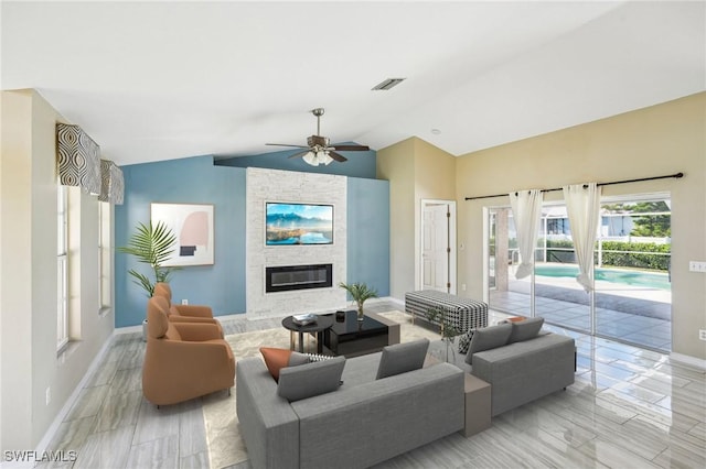 living room featuring ceiling fan, light wood-type flooring, a fireplace, and vaulted ceiling