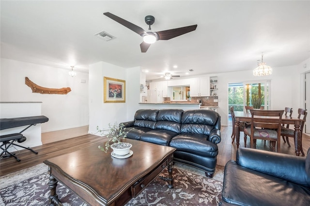 living room with wood-type flooring and ceiling fan with notable chandelier