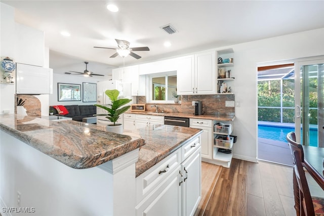 kitchen with white cabinetry, stainless steel dishwasher, kitchen peninsula, white fridge, and light hardwood / wood-style floors