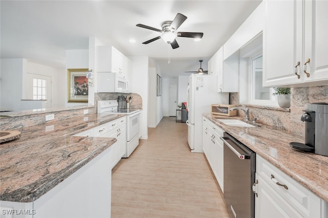 kitchen with white appliances, white cabinets, sink, light stone countertops, and light hardwood / wood-style floors