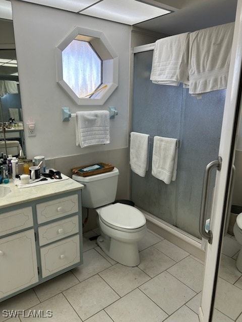 bathroom with tile patterned floors, vanity, walk in shower, and toilet