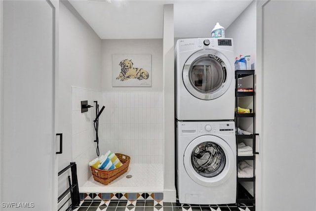 clothes washing area with stacked washing maching and dryer and dark tile patterned floors