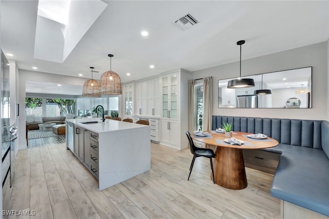 kitchen with breakfast area, white cabinets, light hardwood / wood-style floors, and decorative light fixtures