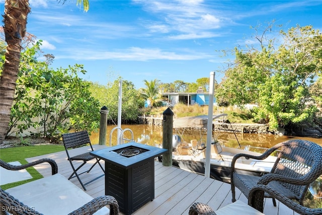 deck with a boat dock, a water view, and an outdoor fire pit