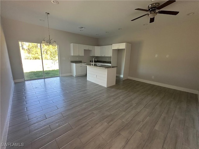 kitchen featuring white cabinetry, sink, light hardwood / wood-style flooring, an island with sink, and decorative light fixtures